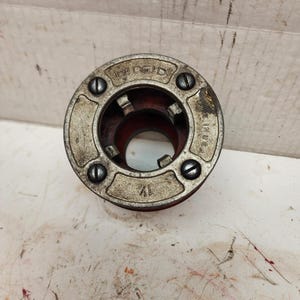 May include: A silver and red pipe die with the word "RIDGID" and "USA" printed on it.