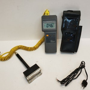 May include: A gray digital thermometer with a yellow coiled cord and a black probe. The thermometer displays a temperature of -0.46 degrees Celsius. The thermometer is in a black leather case.