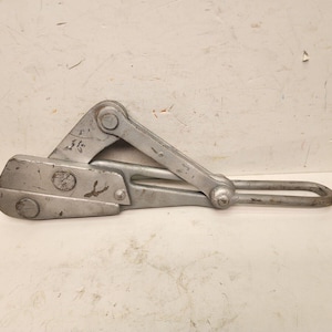 May include: A silver metal cable clamp with a loop on one end and a lever on the other. The clamp has a small metal tag with the number "1" on it.