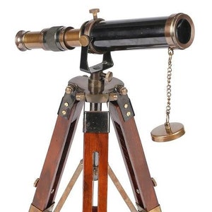Pu&ograve; includere: Un telescopio in ottone con un cannone nero e un treppiede in legno. Il telescopio ha una catena attaccata al cannone e un tappo in ottone all'estremit&agrave; della catena.