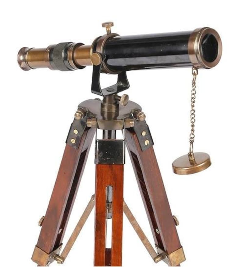 Pu&ograve; includere: Un telescopio in ottone con un cannone nero e un treppiede in legno. Il telescopio ha una catena attaccata al cannone e un tappo in ottone all'estremit&agrave; della catena.