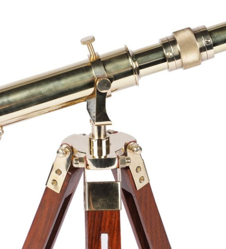 Pu&ograve; includere: Un telescopio in ottone con un treppiede in legno. Il telescopio &egrave; dorato e ha una manopola in ottone sul lato. Il treppiede &egrave; in legno scuro e ha tre gambe.