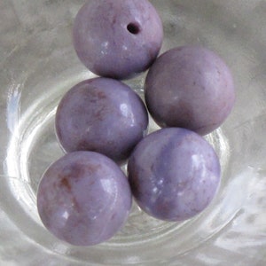 May include: Five round, purple and white marbled beads. The beads are smooth and glossy.