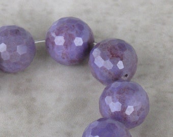 May include: A strand of purple faceted gemstone beads. The beads are round and have a slightly irregular shape. The beads are strung on a silver wire.