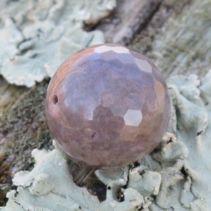 May include: A purple and brown faceted gemstone bead with a small hole in the center.