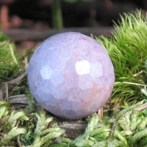 May include: A smooth, round, purple and white agate sphere. The sphere is sitting on a bed of green moss.