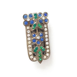 a 3 x 1 centimetre dress clip with rhinestones with two blue flowers with clear centres at the top, green leaves, a flower in the middle and more green leaves at the bottom, with a clear border of rhinestones down either side.