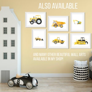 May include: A set of six yellow construction vehicle prints with white frames. The prints feature a tractor, dump truck, excavator, roller, bulldozer, and backhoe. The prints are displayed on a wall in a nursery with a toy car and a toy house.