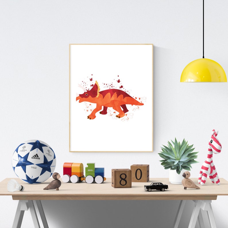 May include: A watercolor painting of a red and orange dinosaur with three horns on its head. The dinosaur is on a white background with splatters of red and orange paint.