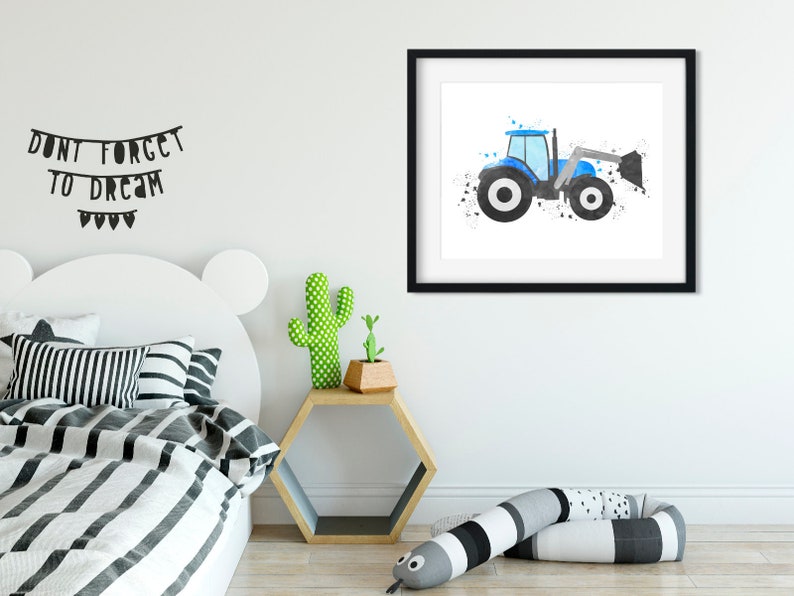 May include: A watercolor painting of a blue tractor with a black and white design. The tractor is on a white background with black splatters of paint. The painting is framed in a black frame and is hanging on a white wall.