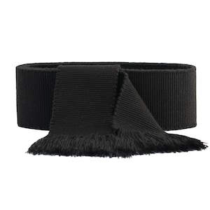 May include: A black fabric scarf with a fringed edge. The scarf is folded in half and tied in a knot.