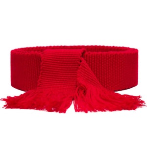 May include: A red knitted belt with long fringe tassels. The belt is made of a thick, woven fabric.