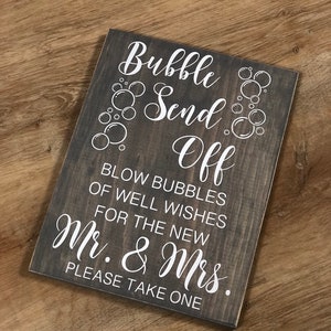 Puede incluir: Un letrero de madera con texto blanco que dice "Bubble Send Off. Blow bubbles of well wishes for the new Mr. & Mrs. Please take one."