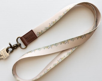 Umhängeband mit einem zierlichen Blumendesign auf hellbraunem Hintergrund, optional mit schwarzem oder braunem Ausweishalter