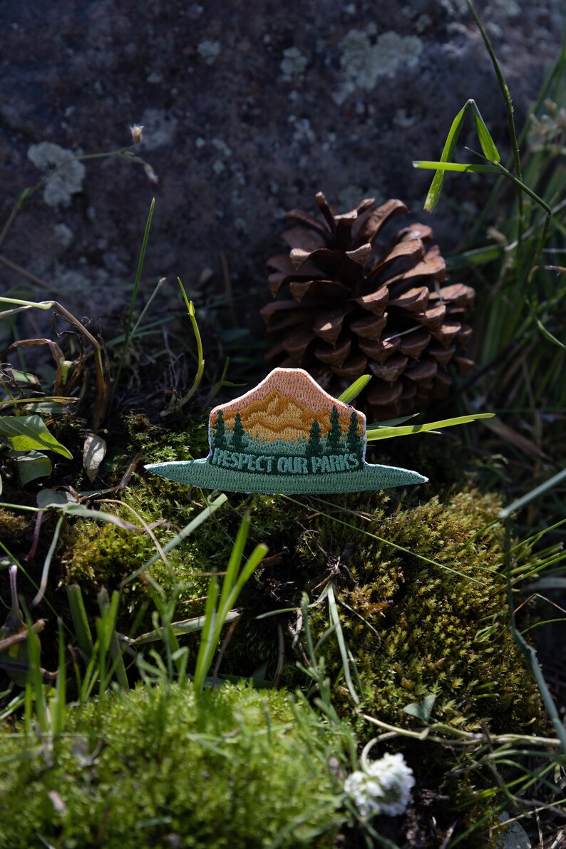 park ranger hat patch laying in moss and pinecones