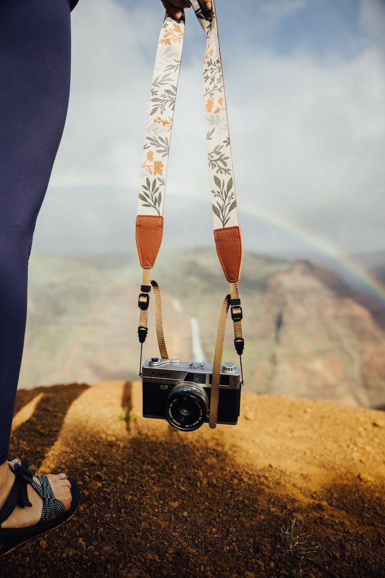 women holding wildflower camera strap attached to vintage camera overlooking the canyon.