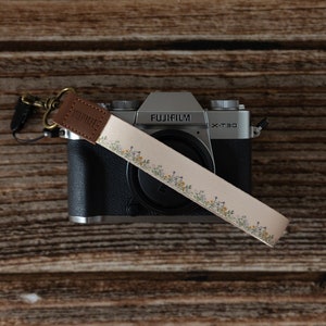 Floral printed keychain. small dainty flowers on tan strap attached to light weight camera