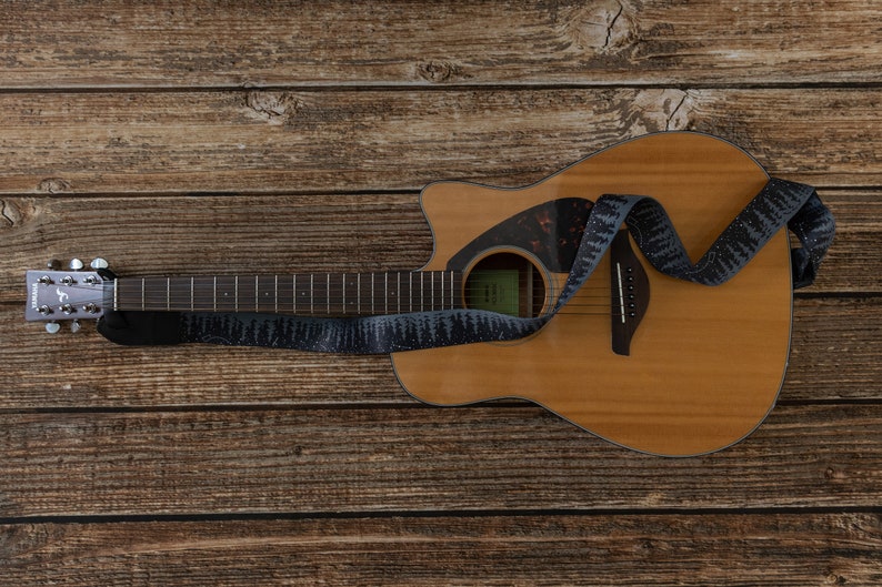 tree line night sky and stars guitar strap attached to the acoustic guitar laying on floor