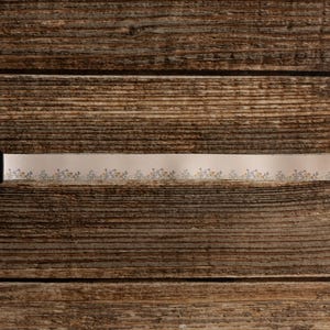Cute tan floral strap printed with Little colored flowers across the length of the strap lying on wood floor