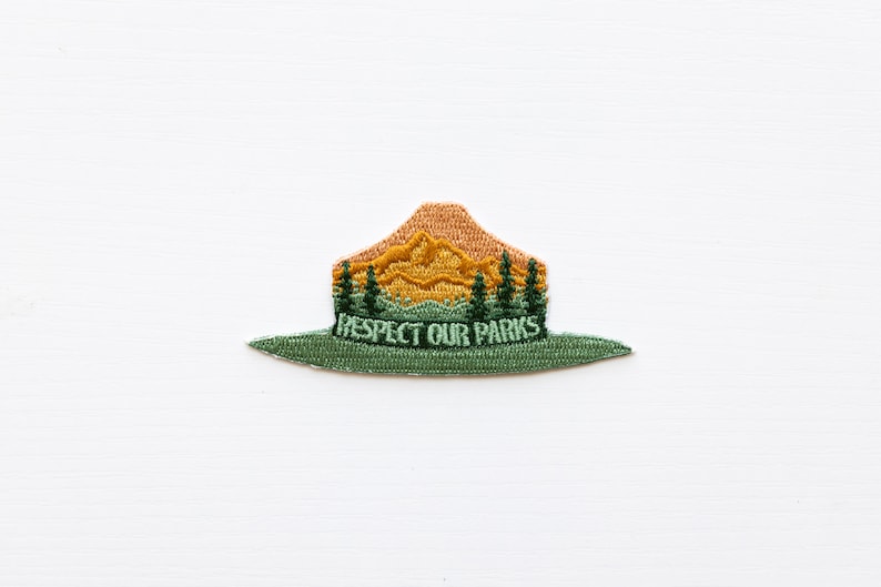 Park Ranger Hat Patch. Green, Orange and yellow patch in the shape of a ranger hat with mountains, trees and the words "respect our parks"