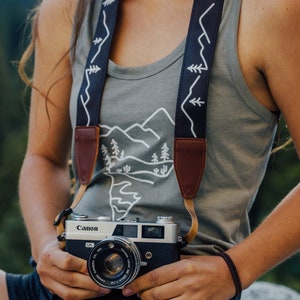 women wearing simple mountain design camera strap holding camera