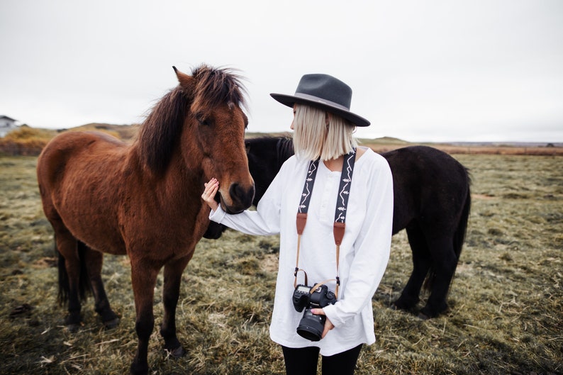 women wearing simple mountain camera strap petting horse