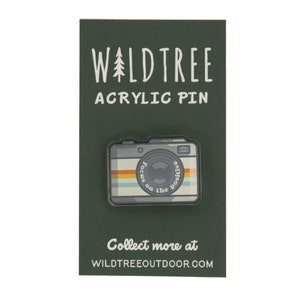 acrylic pin in the shape of a vintage camera with the words around the lens "Focus on the positive"