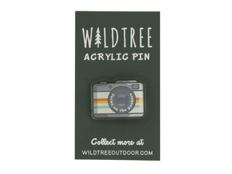 acrylic pin in the shape of a vintage camera with the words around the lens "Focus on the positive"