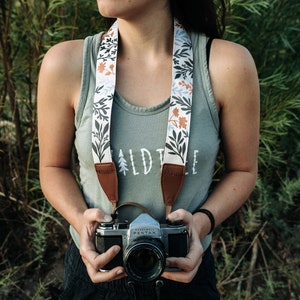 Wildflower Design camera strap with brown leather ends and backing around women neck holding vintage camera