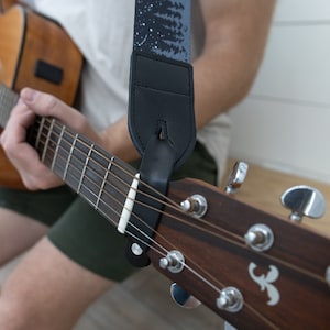 black guitar strap with printed trees and stars