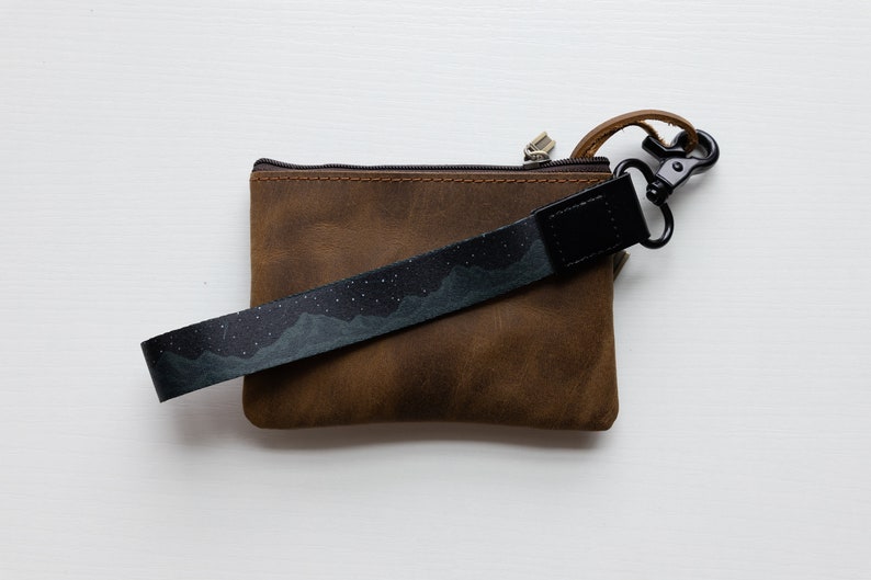 midnight mountain black keychain. Printed with mountains and stars. Attached to brown leather wallet