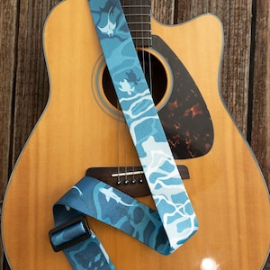 Może przedstawiać: Biały ceramiczny kubek z czarnym uchwytem i napisem "But First, Coffee" w stylu odręcznym. Kubek stoi na białej powierzchni. Kubek ma około 10 cm wysokości.