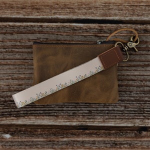 flower printed keychain attached to brown leather coin pouch