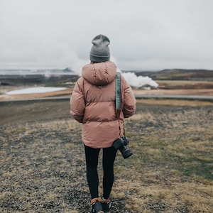 women back turned with Pinetree green camera strap hanging from shoulder