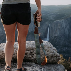 women walking away holding camera by side with Pinetree camera strap attached