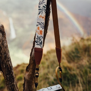 flower camera strap dangling from branch holding camera strap