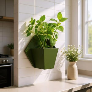 May include: A green, geometric wall planter filled with vibrant green plants. The planter is mounted on a white tiled wall, with a window and a small vase of white flowers in the background. The planter's design adds a modern touch to the kitchen.