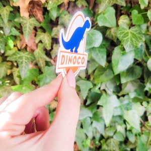 May include: A blue dinosaur silhouette sticker with the word "DINOCO" in orange text on a white oval background.