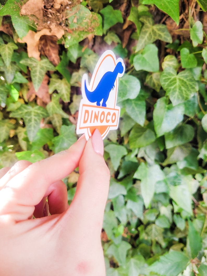 May include: A blue dinosaur silhouette sticker with the word "DINOCO" in orange text on a white oval background.
