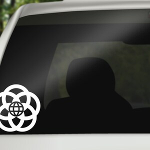 May include: White vinyl decal of the Epcot logo, featuring a globe surrounded by four rings, on a black car window.