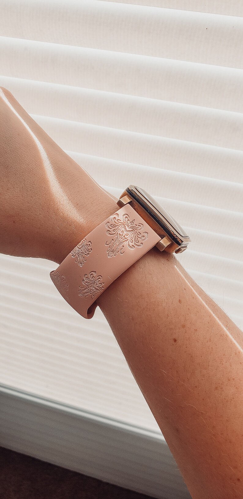 May include: A pink silicone watch band with a gold watch face and a floral pattern.