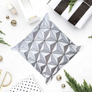 K&ouml;nnte beinhalten: Eine wei&szlig;e Geschenkt&uuml;te mit einem geometrischen Muster in Graut&ouml;nen. Die T&uuml;te liegt flach auf einer wei&szlig;en Oberfl&auml;che mit dekorativen Gegenst&auml;nden drumherum.