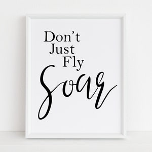 以下が含まれることがあります： 「Don't Just Fly Soar」という黒い文字が書かれた白い額縁付きのプリントです。
