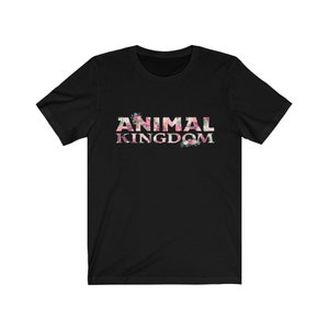 Puede incluir: Camiseta negra con la inscripci&oacute;n "ANIMAL KINGDOM" en un dise&ntilde;o floral. Las letras est&aacute;n rellenas de flores rosas, blancas y verdes. La camiseta tiene cuello redondo y mangas cortas, ideal para un look casual.