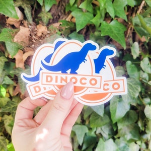 May include: Two blue dinosaur silhouette stickers with an orange circle and the text "Dinoco Co." in white.