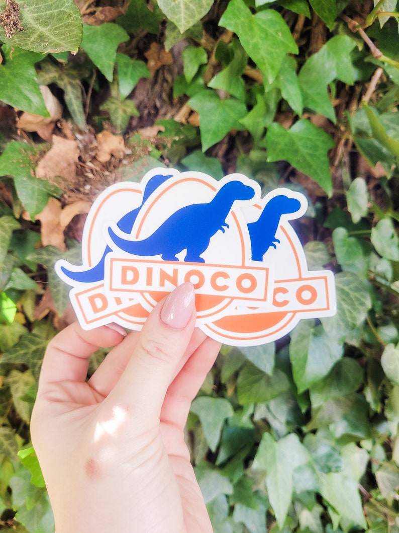 May include: Two blue dinosaur silhouette stickers with an orange circle and the text "Dinoco Co." in white.