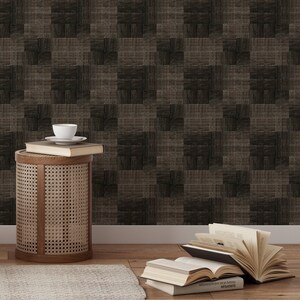 Könnte beinhalten: Zimmerszene mit braun-schwarzer Tapete. Ein kleiner, runder Beistelltisch aus Holz mit geflochtenem Rohrdesign hält Bücher und eine weiße Tasse und Untertasse. Bücher liegen auch auf dem Holzboden.
