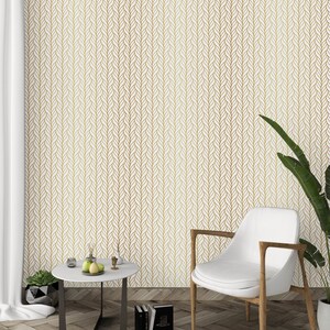 Puede incluir: Una silla blanca con patas de madera se encuentra frente a una pared blanca con un patr&oacute;n geom&eacute;trico dorado. Una peque&ntilde;a mesa redonda con una tapa blanca y patas negras se encuentra frente a la silla. La mesa tiene una peque&ntilde;a planta en maceta y un taz&oacute;n de fruta.