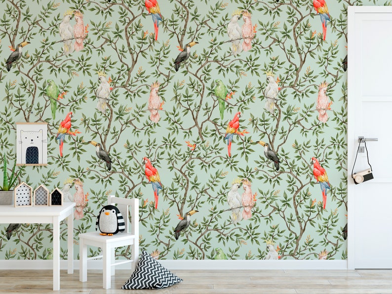 May include: Watercolor wallpaper featuring a repeating pattern of colorful parrots, toucans, and cockatoos perched on leafy branches against a light green background. The room includes a white table, chair, and decorative items.