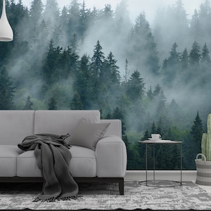 May include: A living room scene featuring a gray sofa with a dark gray throw blanket and pillow. A forest mural is on the wall behind the sofa. A small side table holds a cup and saucer. A cactus in a woven basket sits nearby.